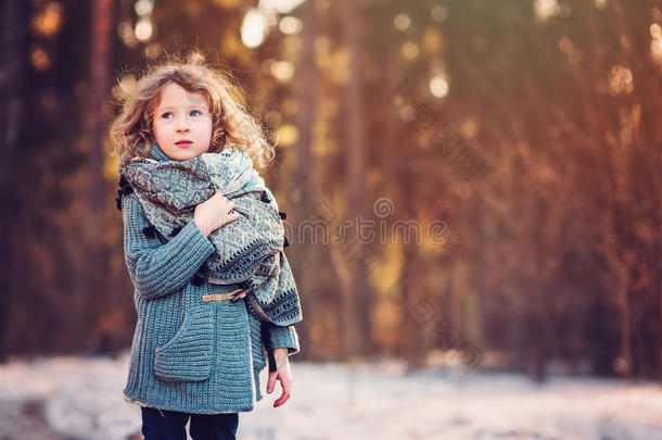 穿着灰色针织外套的可爱女孩在冬天的森林里散步