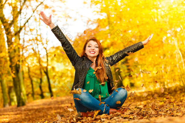 秋天公园里放松的女孩把树叶抛向空中。
