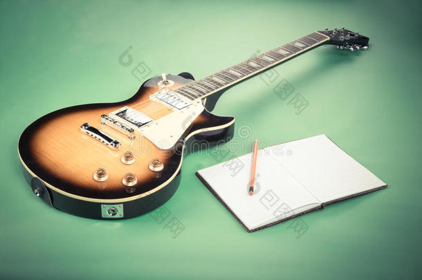 电吉他与笔记本笔记在绿色背景。 过滤后的复古图像
