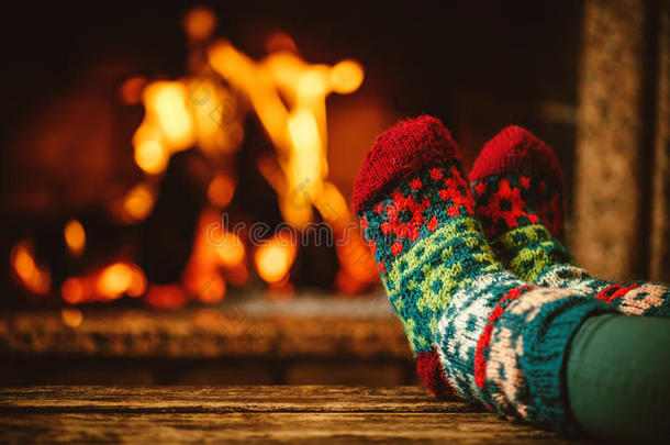 穿着羊毛袜子的脚在壁炉边。 女人通过温暖放松