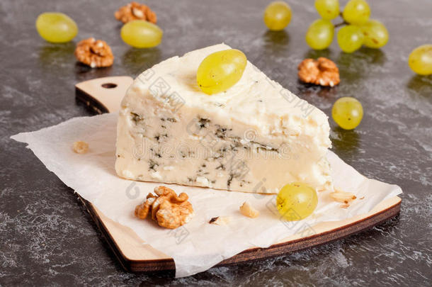 蓝色奶酪，木制切割板上有葡萄和坚果