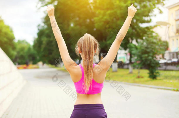 健身快乐跑步妇女享受训练后在城市公园，跑步冠军，举手，运动和健康的生活方式