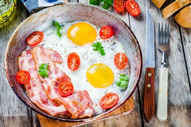早餐有煎鸡蛋、培根、西红柿和欧芹