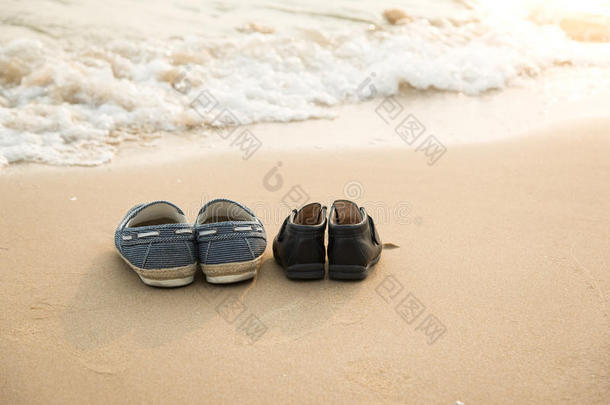 更远的鞋子和儿子的鞋子在海滩上