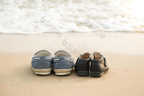 更远的鞋子和儿子的鞋子在海滩上