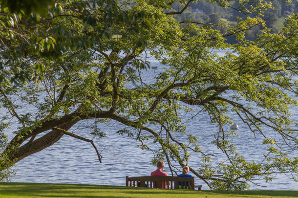 一对夫妇坐在长凳上，凝视着坎布莱德的温特雷米尔湖