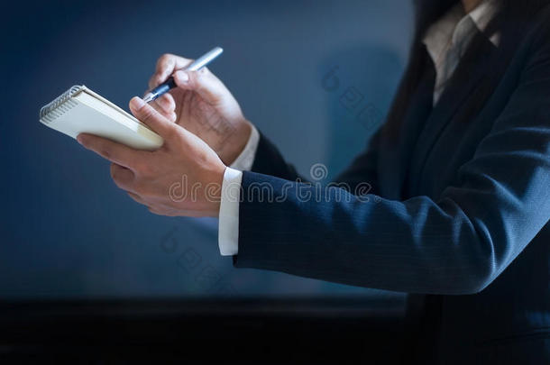 商务妇女在深蓝色背景的纸上做笔记