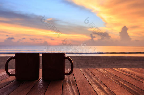 日落或日出海滩木桌上的咖啡杯