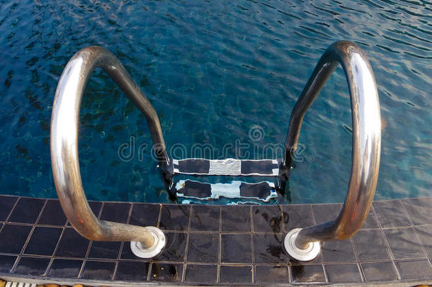 用石头在蓝色游泳池里的抓杆梯子