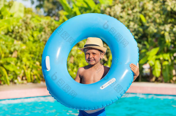 戴帽子的男孩，在游泳池附近拿着充气环