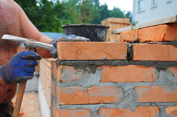 砖工用砌砖锤在室外建造新的红色砖墙。 砌砖基础砌筑技术。