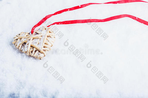 美丽神奇的复古米色心系在白色雪背景上的红色丝带