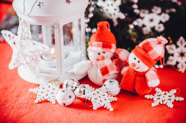 可爱的一对小雪人站在白色仙女灯笼附近，上面有一颗玩具心，装饰着杉木树枝。
