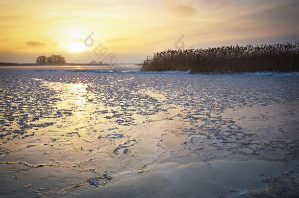 美丽的冬季风景，冰封的湖面和夕阳的天空。