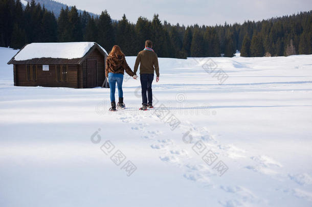 一对夫妇玩得开心，穿着雪鞋散步