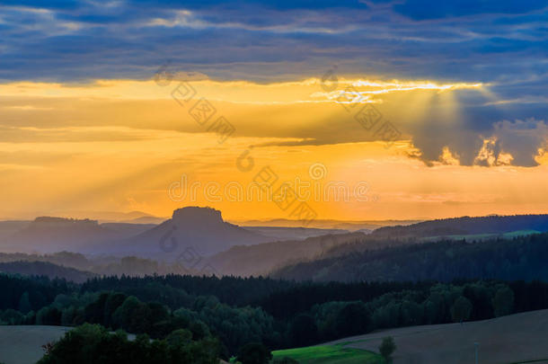 美丽的夕阳笼罩着连绵起伏的山丘，<strong>阳光穿透</strong>天空，照亮了山坡