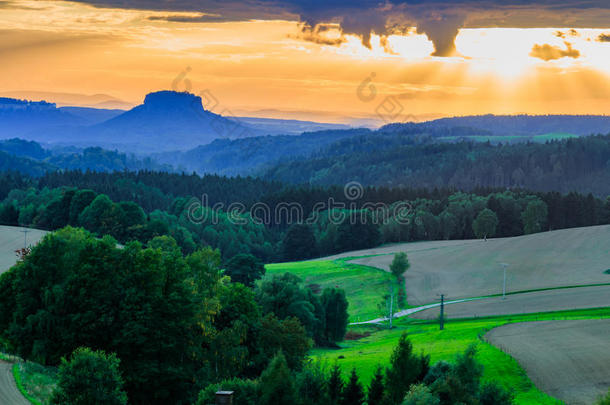 美丽的夕阳笼罩着连绵起伏的山丘，阳光穿透天空，照亮了山坡