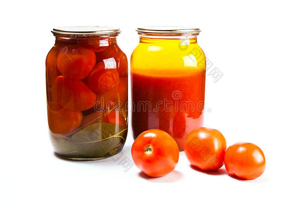 白色背景上罐装西红柿和西红柿汁的玻璃瓶。 成熟的西红柿在玻璃瓶前。