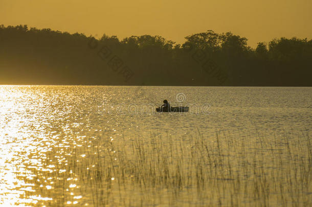 日落时男孩在皮艇里钓鱼