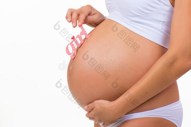 在水平白色背景下，用粉红色标签女孩为新生女儿特写怀孕的肚子