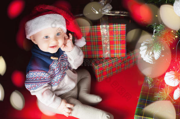圣诞宝宝坐在圣诞树和礼品盒附近！