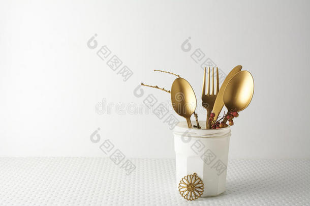 节日的金色餐具刀叉勺子在白色的瓶子里，