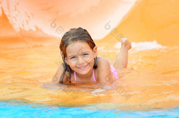 可爱的蹒跚学步的女孩在水上滑梯在水上