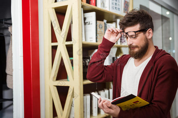 蓄着胡子的年轻人站在书架附近看书