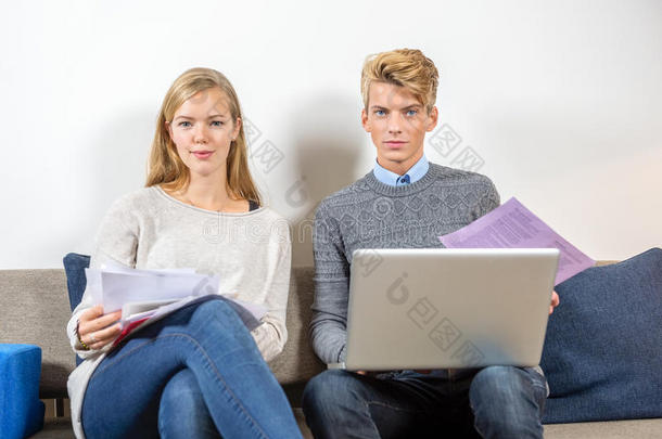 一对夫妇坐在沙发上拿着<strong>收据</strong>和笔记本<strong>电脑</strong>