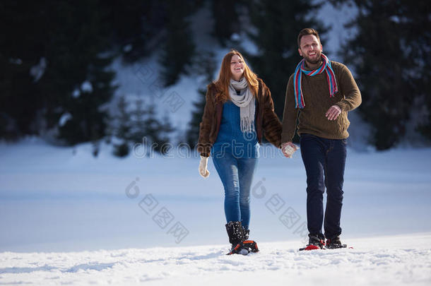 一对夫妇玩得开心，穿着雪鞋散步