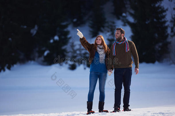 一对夫妇玩得开心，穿着雪鞋散步