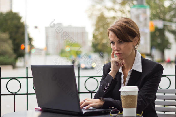 在户外咖啡店用笔记本电脑工作的商人