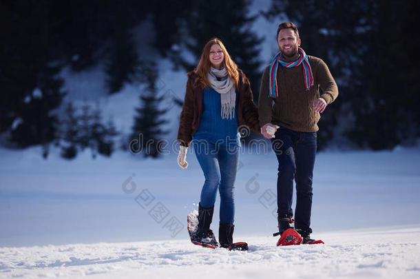 一对夫妇玩得开心，穿着雪鞋散步