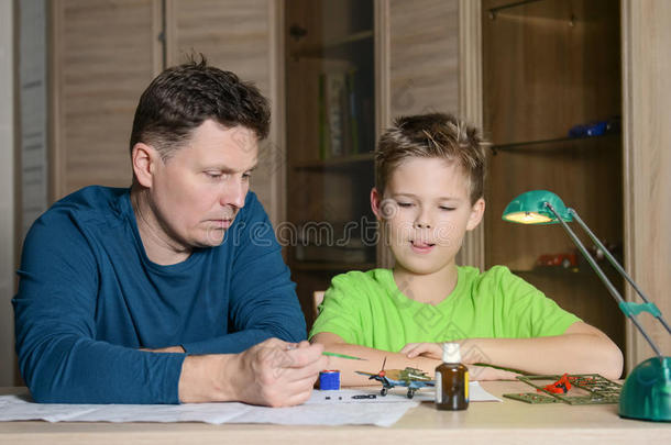 父亲帮他儿子做<strong>飞机模型</strong>。 男人和男孩正在做<strong>飞机模型</strong>。