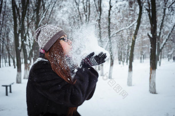 美丽<strong>的冬天</strong>女孩在<strong>寒冷的冬天</strong>公园里吹雪