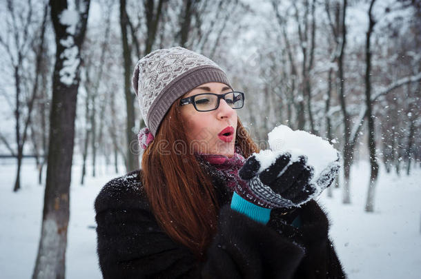 美丽的冬天女孩在寒冷的冬天公园里吹雪