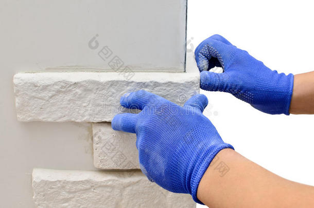 面对<strong>墙壁装饰</strong>瓷砖，工人戴着蓝色手套
