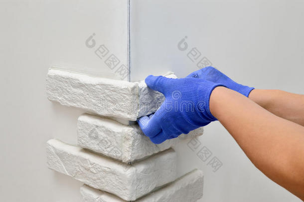 面对<strong>墙壁装饰</strong>瓷砖，工人戴着蓝色手套