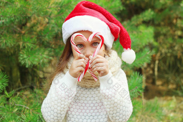 圣诞概念-孩子戴着圣塔红帽，戴着甜蜜的棒棒糖拐杖