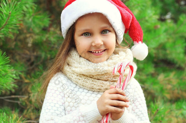 圣诞概念-肖像小微笑女孩戴着圣塔红帽与甜蜜的棒棒糖<strong>拐杖</strong>
