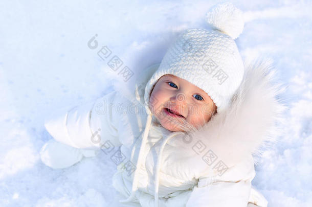 <strong>可爱</strong>的小<strong>宝宝</strong>穿着白色夹克，戴着白色的<strong>帽子</strong>，坐在冬天的雪里