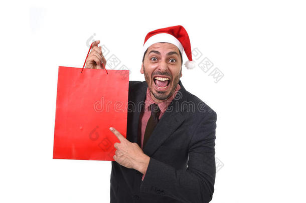 有趣的商人在圣诞节圣诞老人帽子拿着红色购物袋在十二月和新年销售