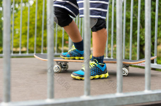 一只脚踩在坡道顶部的滑板上的男孩