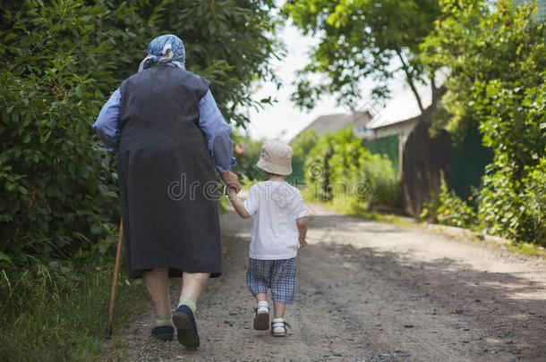 曾祖母和蹒跚学步的男孩在街上散步时牵手