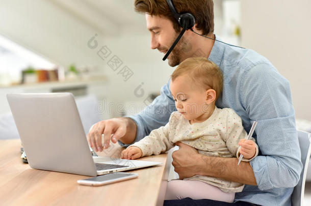 忙碌的年轻父亲和他的孩子在笔记本电脑上工作