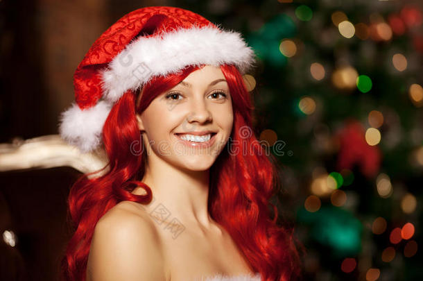 圣诞树旁年轻美丽微笑的圣诞老人。女孩在庆祝新年。
