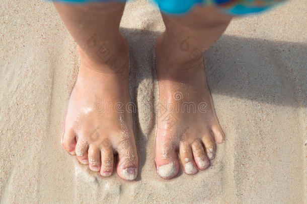 光脚的孩子站在海滩上，俯视图