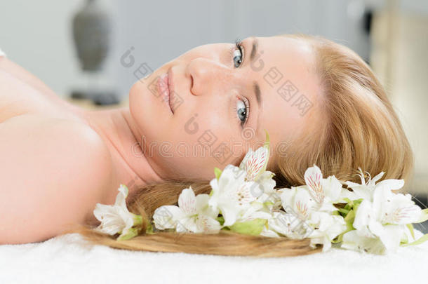 美丽的女人裹着毛巾，躺在水疗中心，白色的水流