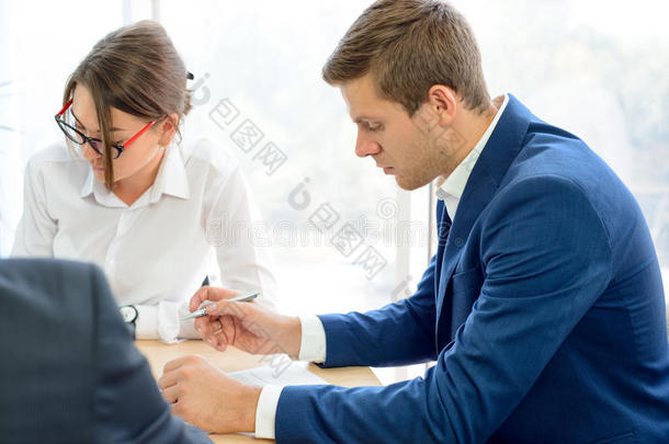 商务人士在现代办公室的桌子周围签署合同。 商业合作理念