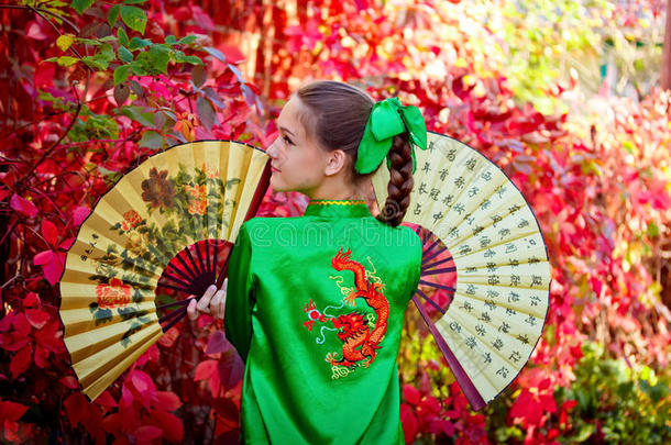 穿着<strong>中国服装</strong>的女孩在红叶的背景上
